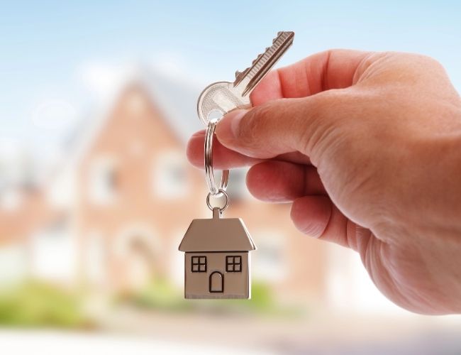 New house key on keyring with a house charm held in a person's hand