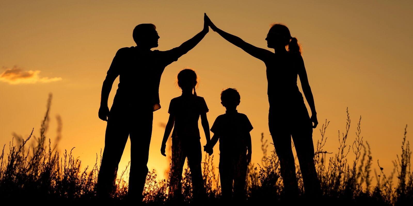 Silhouette of a happy family standing in the park at sunset